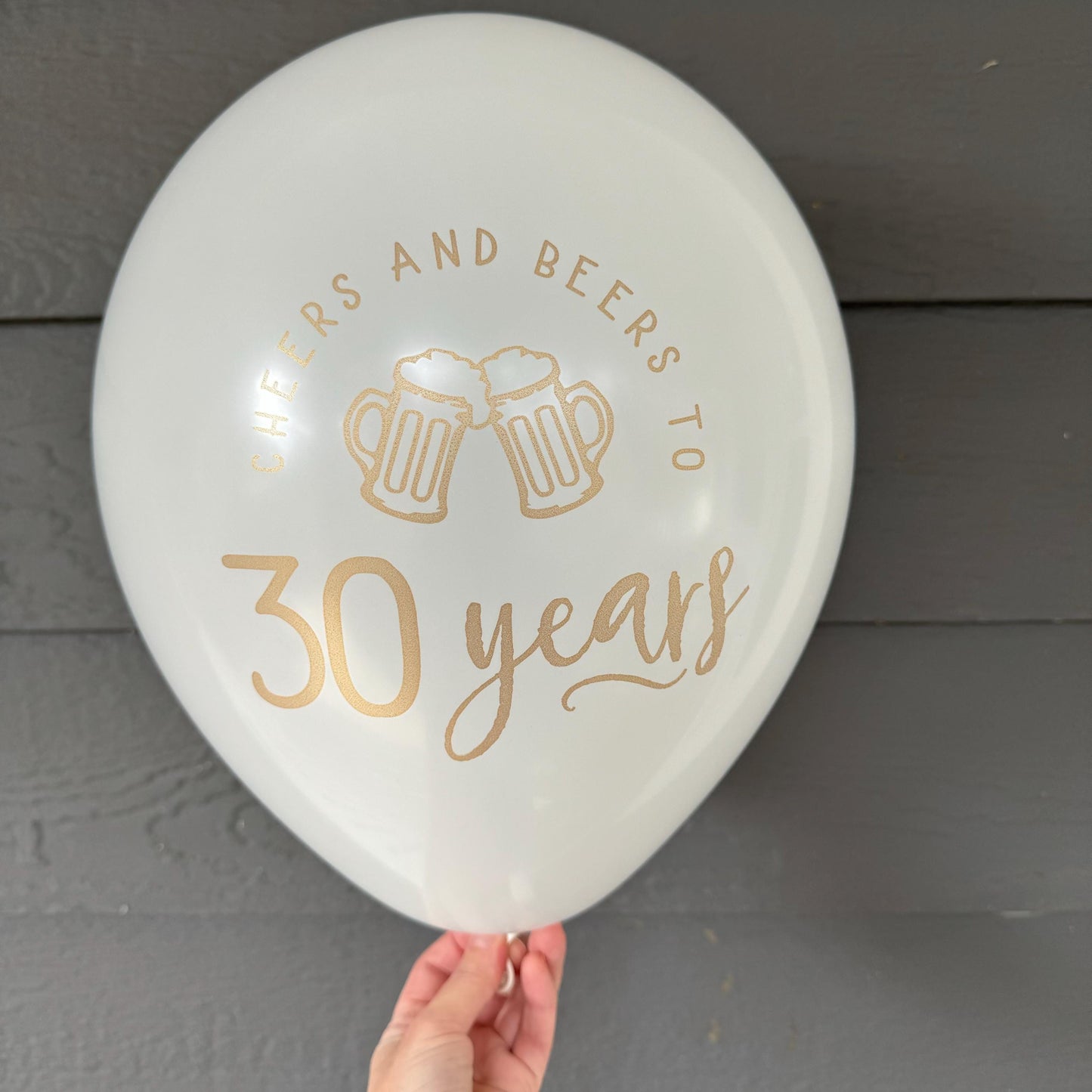 White 12 inch latex balloon that reads cheers and beers to 30 years in a gold metallic font with two beer mugs.
30th birthday balloon