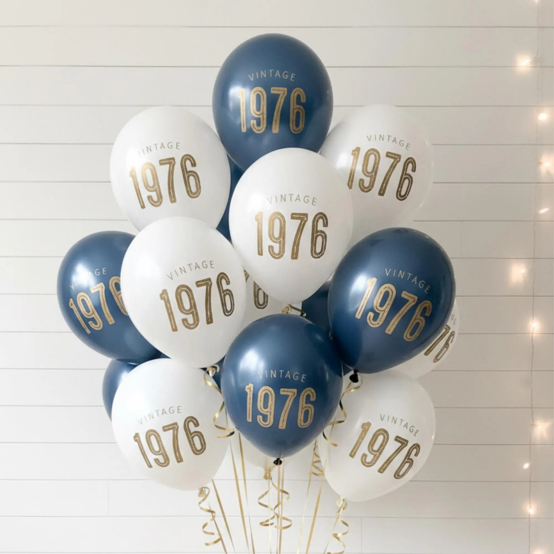 50th Birthday balloons.  A balloon bouquet of navy and white balloons that read Vintage 1976 in bold gold font.  Perfect 50th Birthday Decor for a milestone celebration