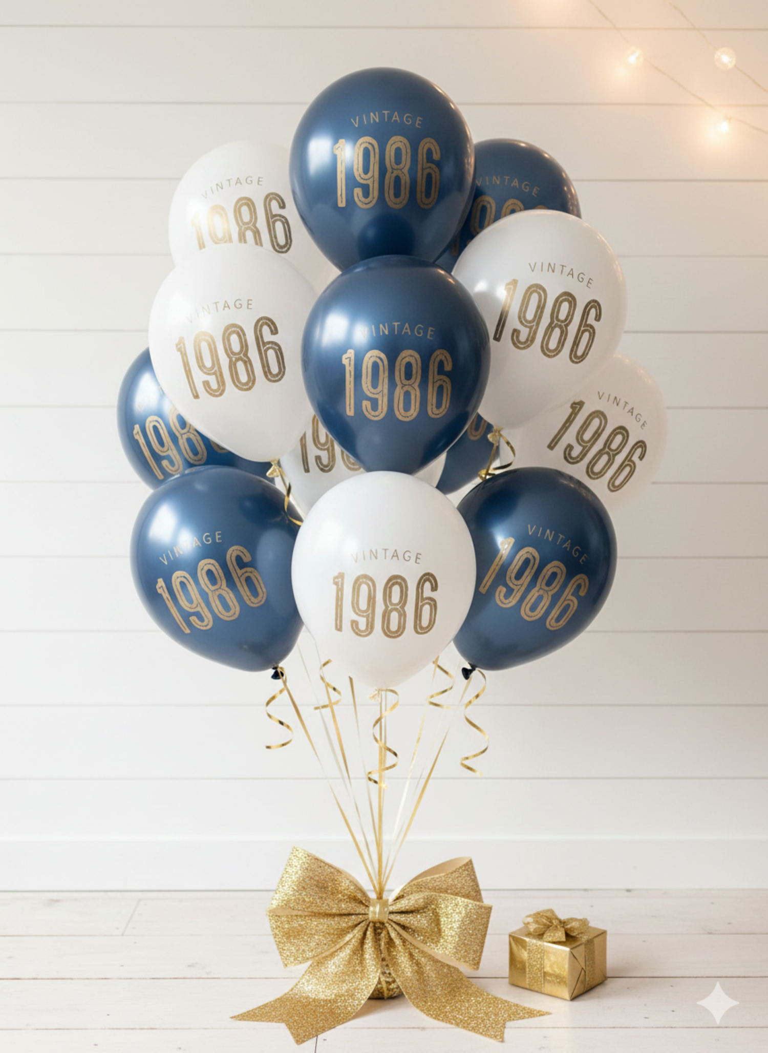 Balloons with '1986' printed on them, tied together with a gold ribbon on a white wooden background.