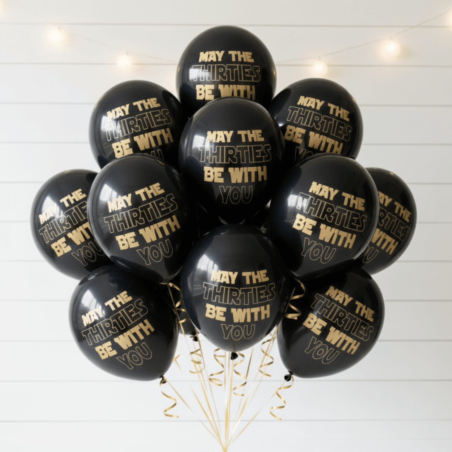 30th Birthday Balloons Black with gold text 'May the Thirties be with you' on a white wooden background