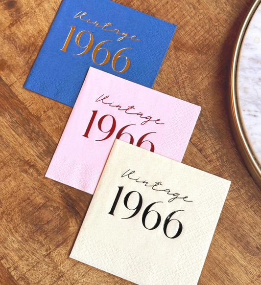 Three cocktail napkins with 'Vintage 1966' text on a wooden surface