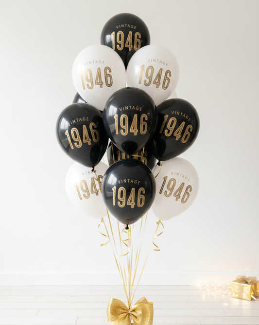Bouquet of balloons with '1946' printed on them, tied with a gold ribbon against a white background.