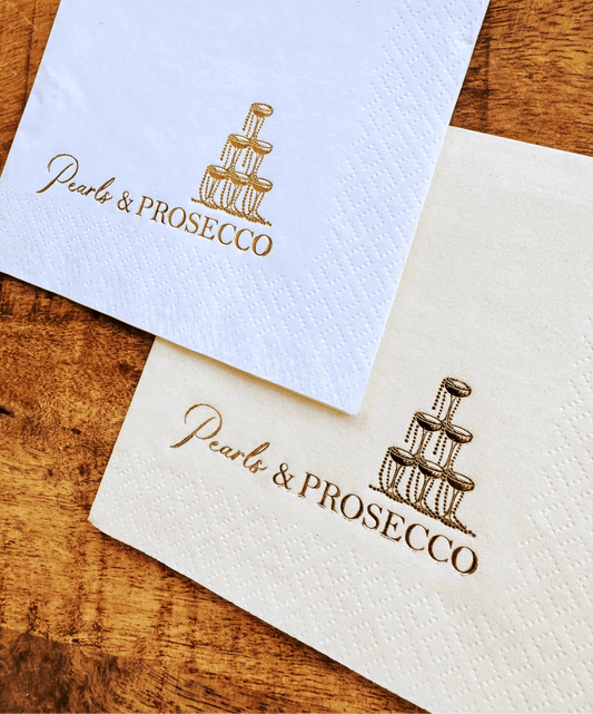 Pearls and Prosecco cocktail napkins that are stamped in gold foil with a champagne tower
