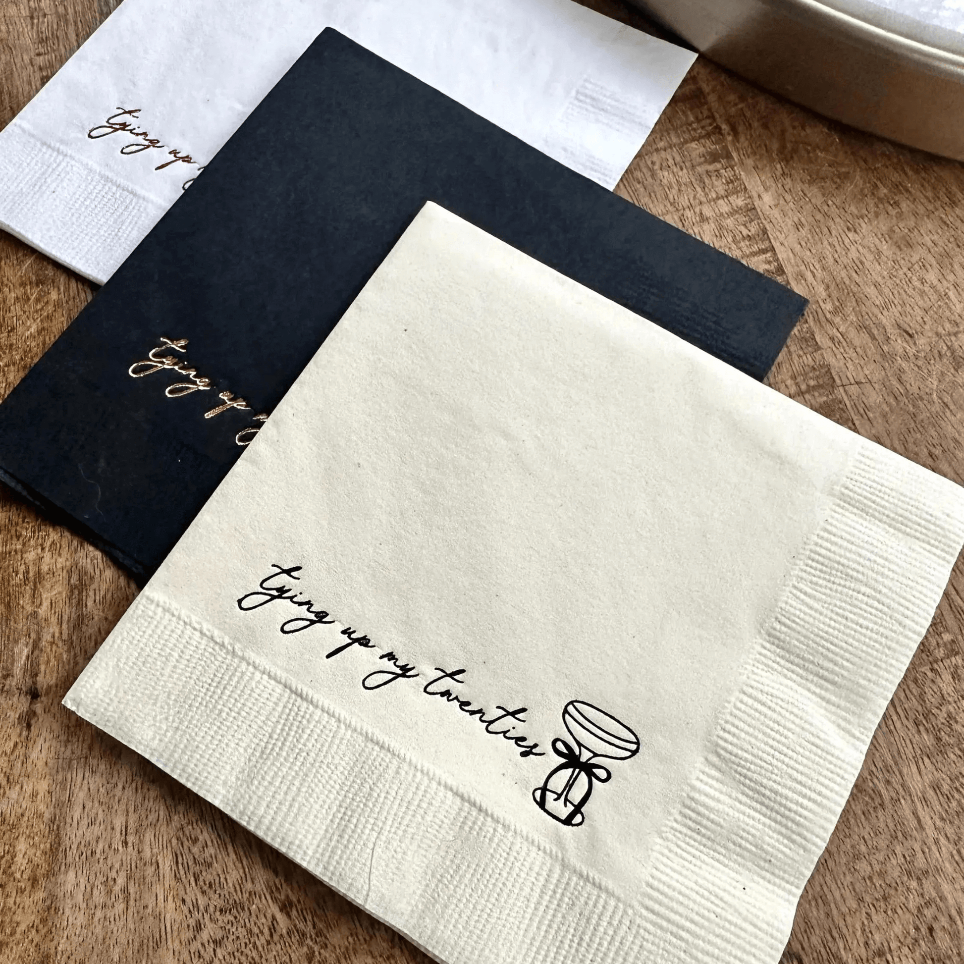 cream, black and pink cocktail napkins that read tying up my twenties, with a martini glass with a bow on the stem.   Stamped in gold and black foil.  for a 30th Birthday Celebration.  Tying up my twenties cocktail napkins.  30th Birthday Decorations