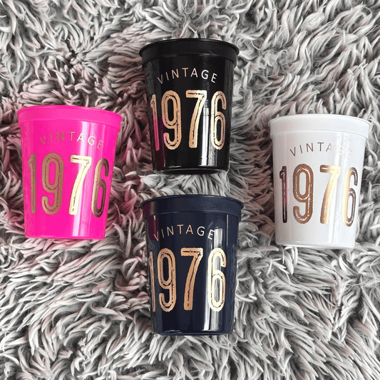 Vintage 1976 stadium cups in black, white, hot pink and navy with gold text