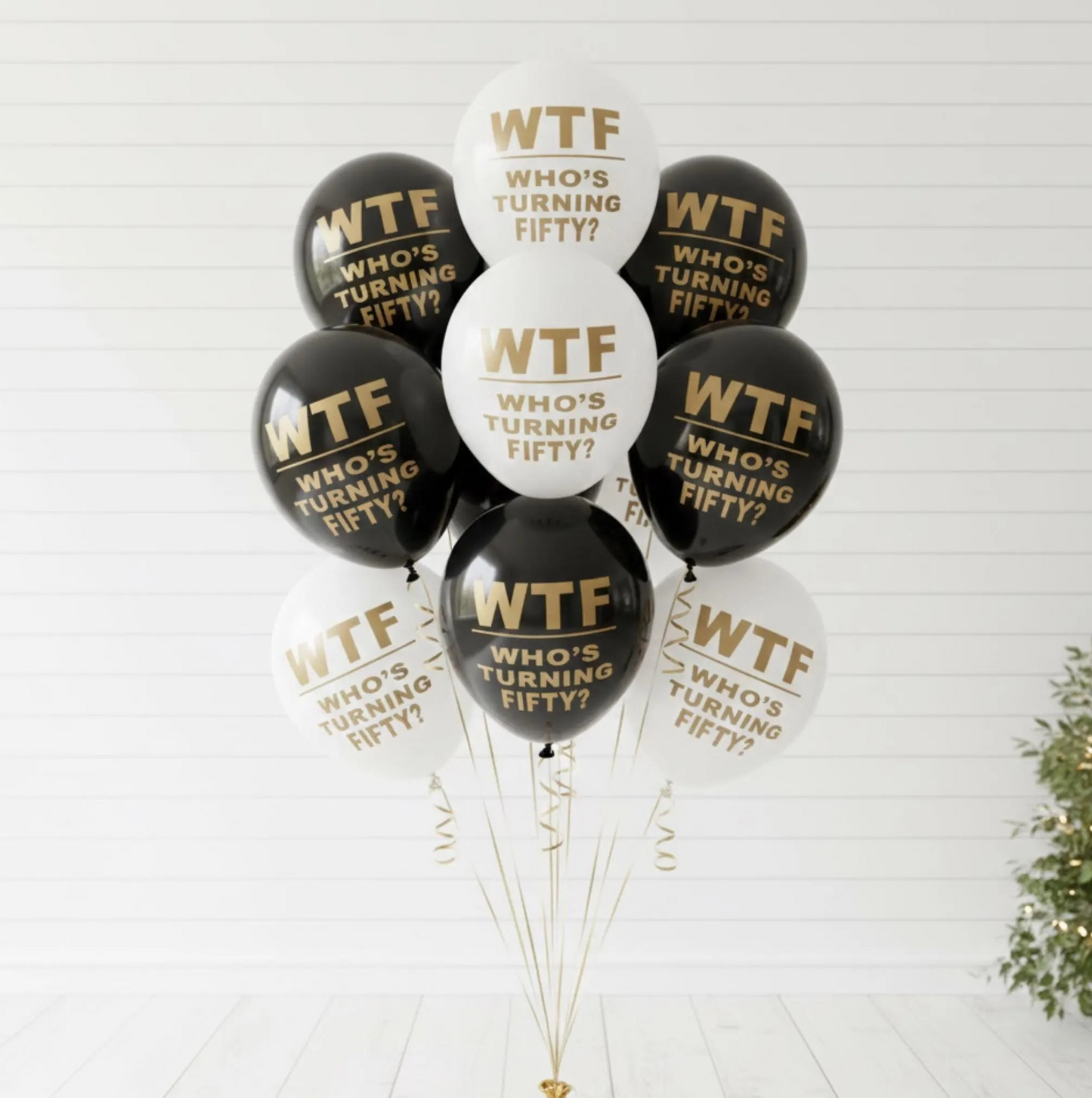 Balloon Bouquet for a 50th Birthday.  The balloons are black and white and read WTF Who's turning fifty? in gold text.