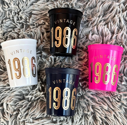 Four 'Vintage 1986' cups in different colors on a textured surface.