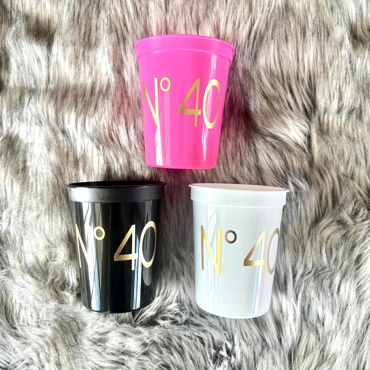 Coordinating No 40 party cups in pink, black and white with gold lettering on gray faux fur.