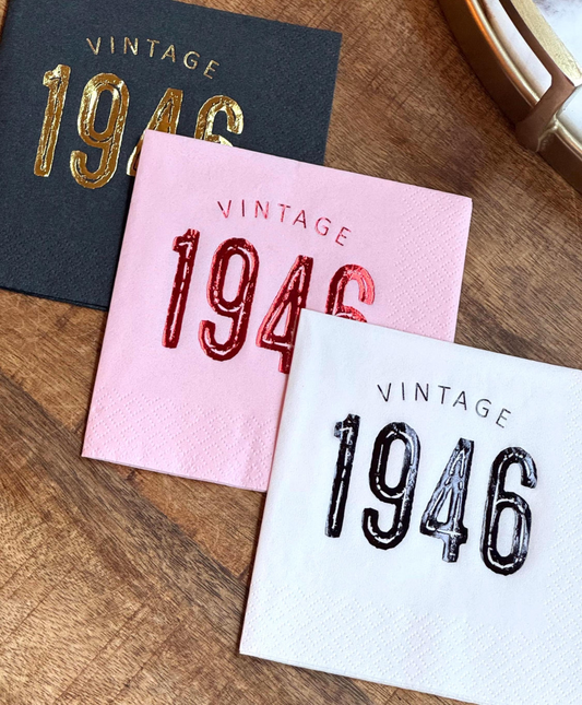 Three 'Vintage 1946' themed napkins on a wooden surface.
