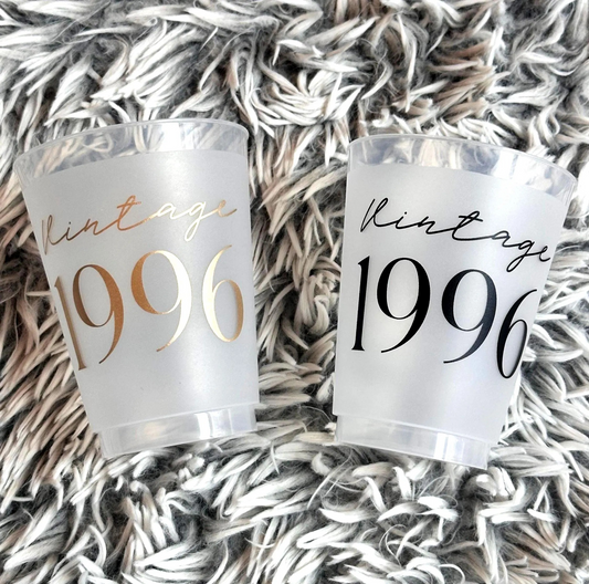 Two clear plastic cups with 'Vintage 1996' text on a textured surface